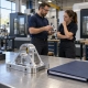 Generic machined bracket and project folder with manufacturing professionals in a CNC shop